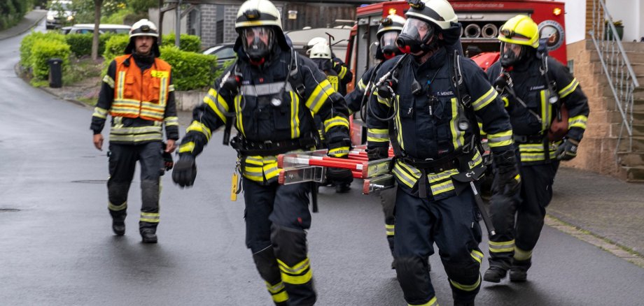 Feuerwehrmänner tragen Steckleiter zum Einsatzort 