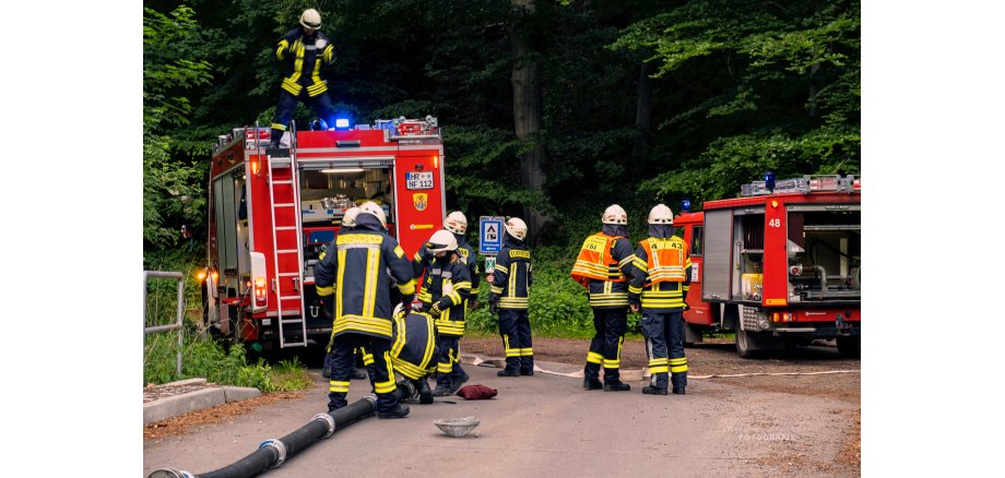 Feuerwehrleute beraten sich und bauen die Schlauchstrecke zum Löschen auf